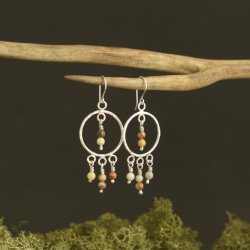 Sterling silver chandelier style earrings featuring 6 4mm crazy lace agate beads suspended on balled headpins.  They are shown against a black background with natural green moss towards the bottom.