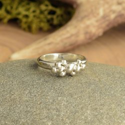 Silver ring featuring organically formed molten silver balls attached to a hammer textured d-shaped band.  sitting on a grey stone with natural moss and an antler in the background